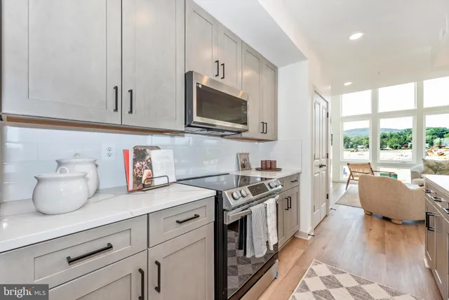 a kitchen with stainless steel appliances granite countertop a stove a sink dishwasher and white cabinets with wooden floor