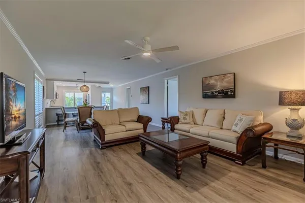 a living room with furniture a flat screen tv and a wooden floor