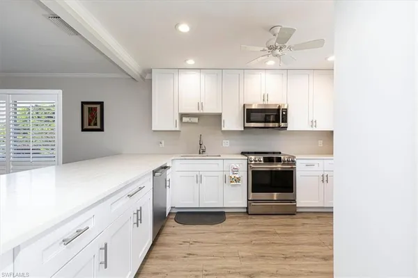 a kitchen with granite countertop white cabinets and stainless steel appliances