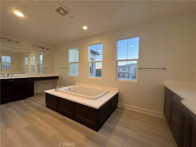 a living room with stainless steel appliances kitchen island a sink dishwasher a stove and a refrigerator with wooden floor