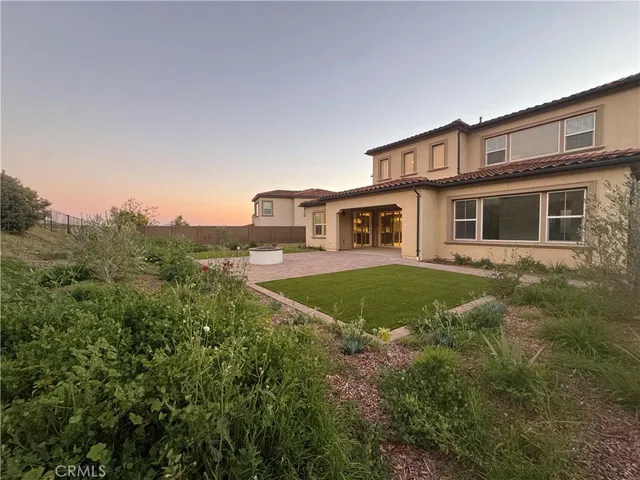 a view of house in front of a big yard with large trees