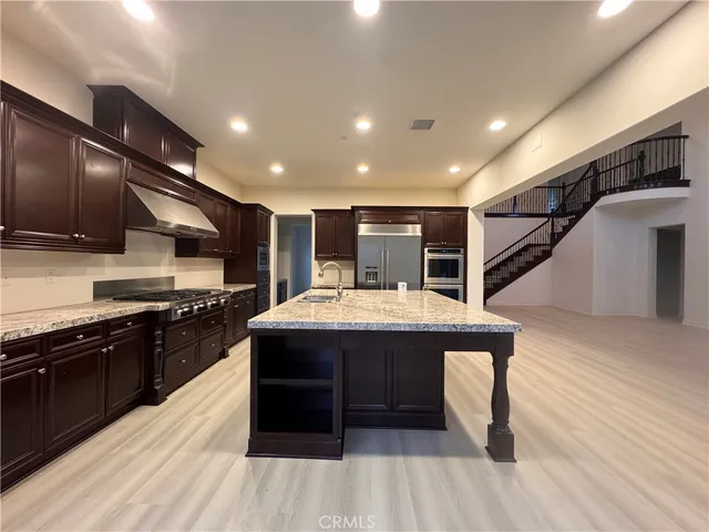 a kitchen with stainless steel appliances kitchen island granite countertop a stove and a wooden floors