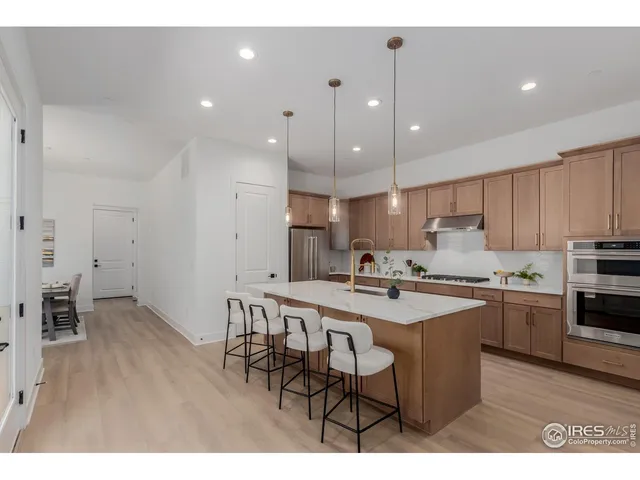 a kitchen with stainless steel appliances granite countertop a sink a stove a refrigerator and island with wooden floor