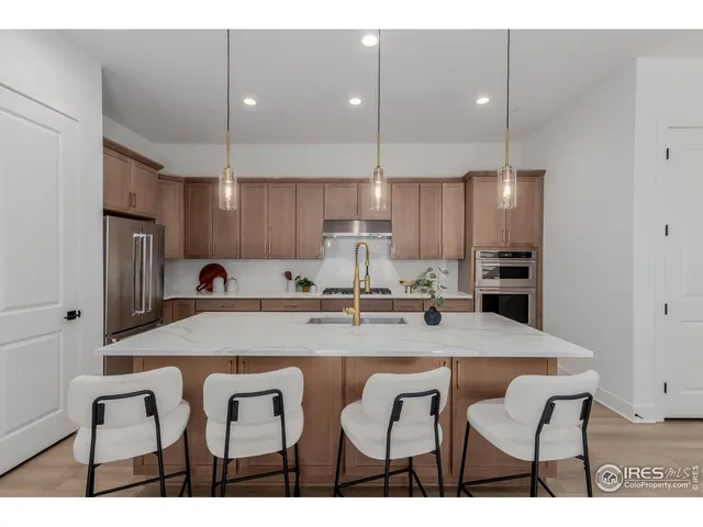 a kitchen with stainless steel appliances kitchen island a table chairs in it and wooden floors