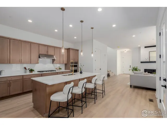 a kitchen with stainless steel appliances kitchen island granite countertop a table chairs sink and cabinets