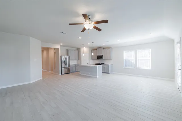 a view of an empty room with window and wooden floor