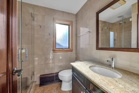 a bathroom with a granite countertop sink a toilet and shower