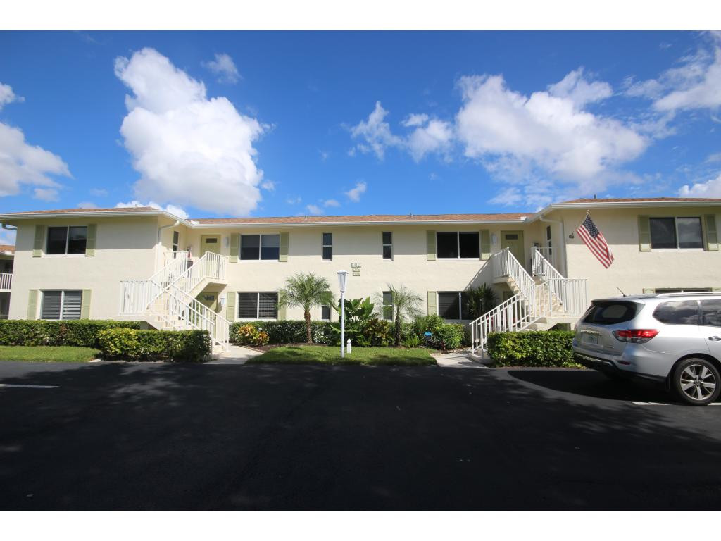 a view of a white house with a big yard and large tree