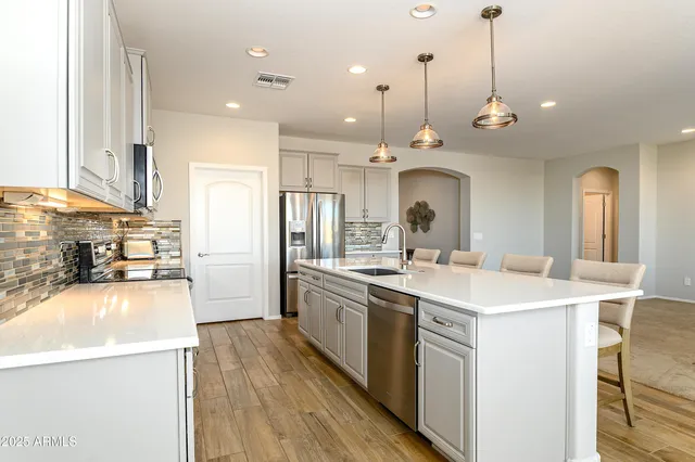 a large kitchen with kitchen island a stove a sink a center island and wooden floor