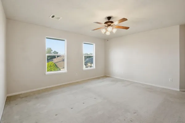 an empty room with windows and fan