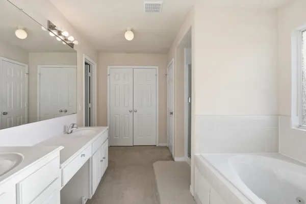 a spacious bathroom with a tub sink and mirror