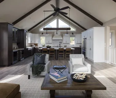 a living room with stainless steel appliances furniture a rug and a kitchen view