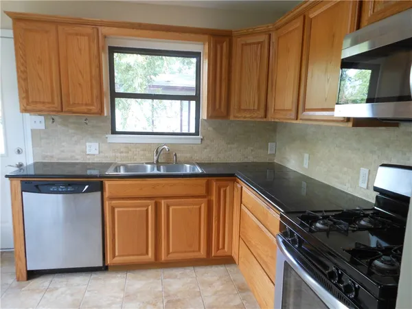 a kitchen with granite countertop a sink window and cabinets