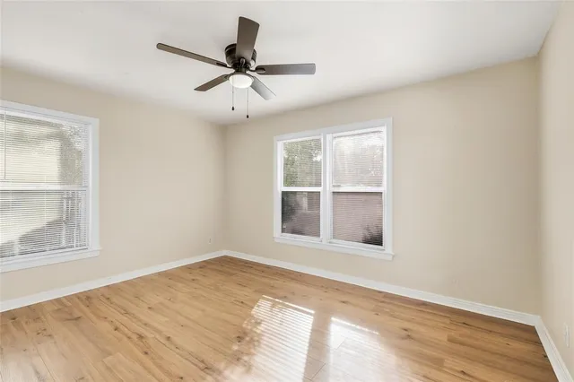 a view of an empty room with a window and wooden floor