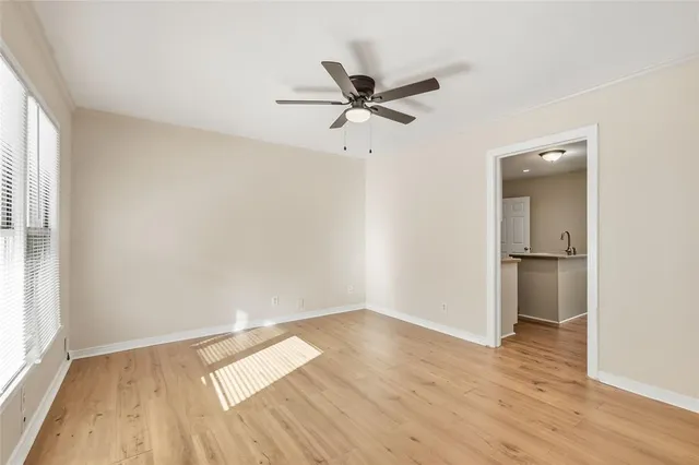 an empty room with wooden floor a ceiling fan and windows
