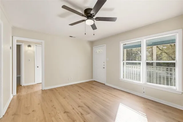 a view of an empty room with a window and wooden floor