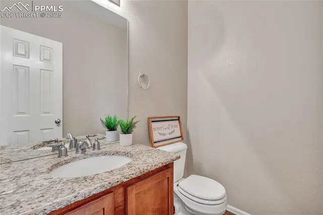 a bathroom with a granite countertop sink mirror vanity and toilet