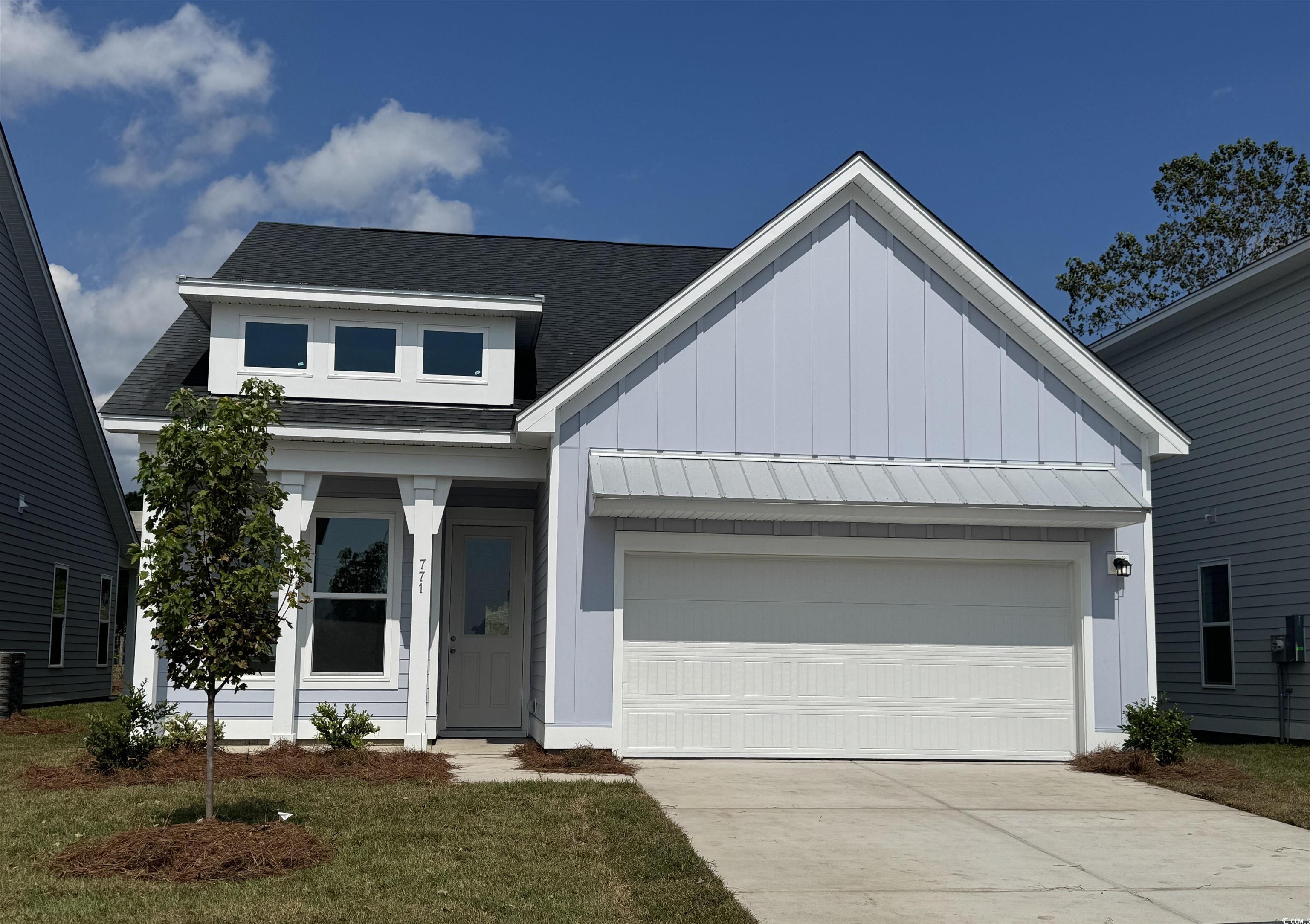 View of front of house featuring a shingled roof, board and batten siding, a garage, driveway, and a front yard