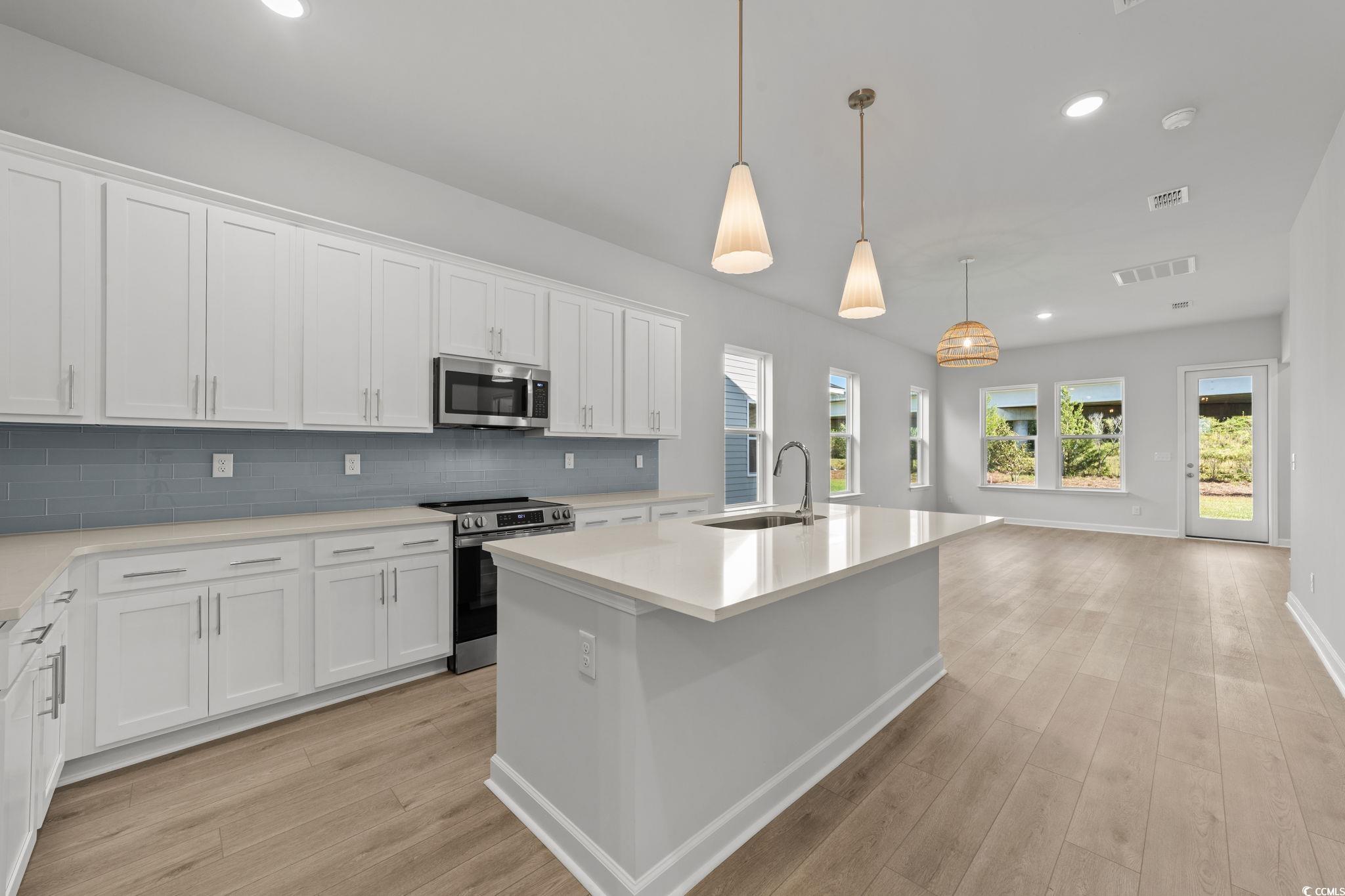 771 Ebb Tide Road Little River, SC 29566 - Photo 16 of 35 Kitchen featuring recessed lighting, white cabinets, stainless steel appliances, decorative backsplash, and a kitchen island with sink