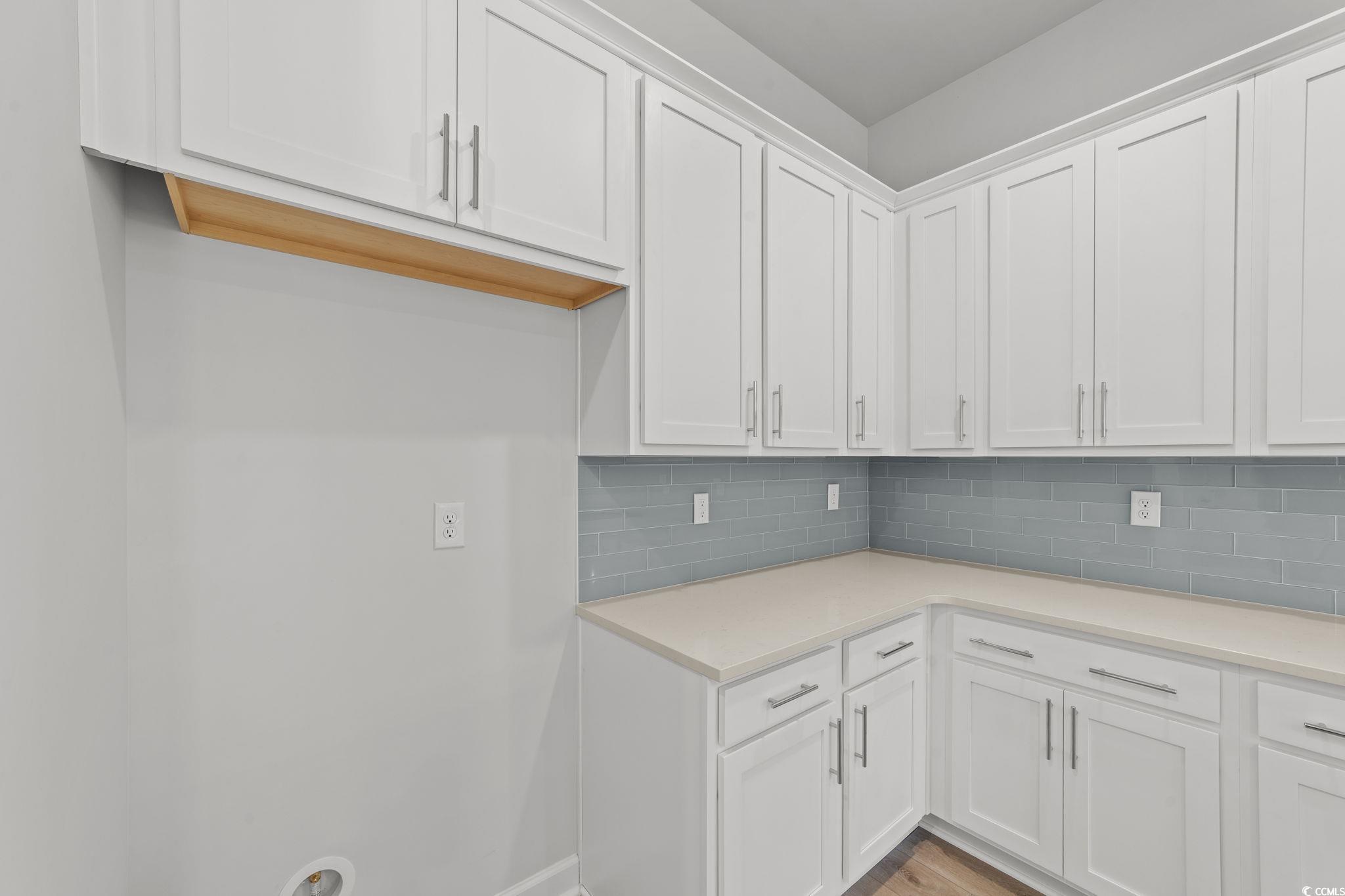 771 Ebb Tide Road Little River, SC 29566 - Photo 19 of 35 Kitchen featuring white cabinets, tasteful backsplash, light stone counters, and light wood finished floors