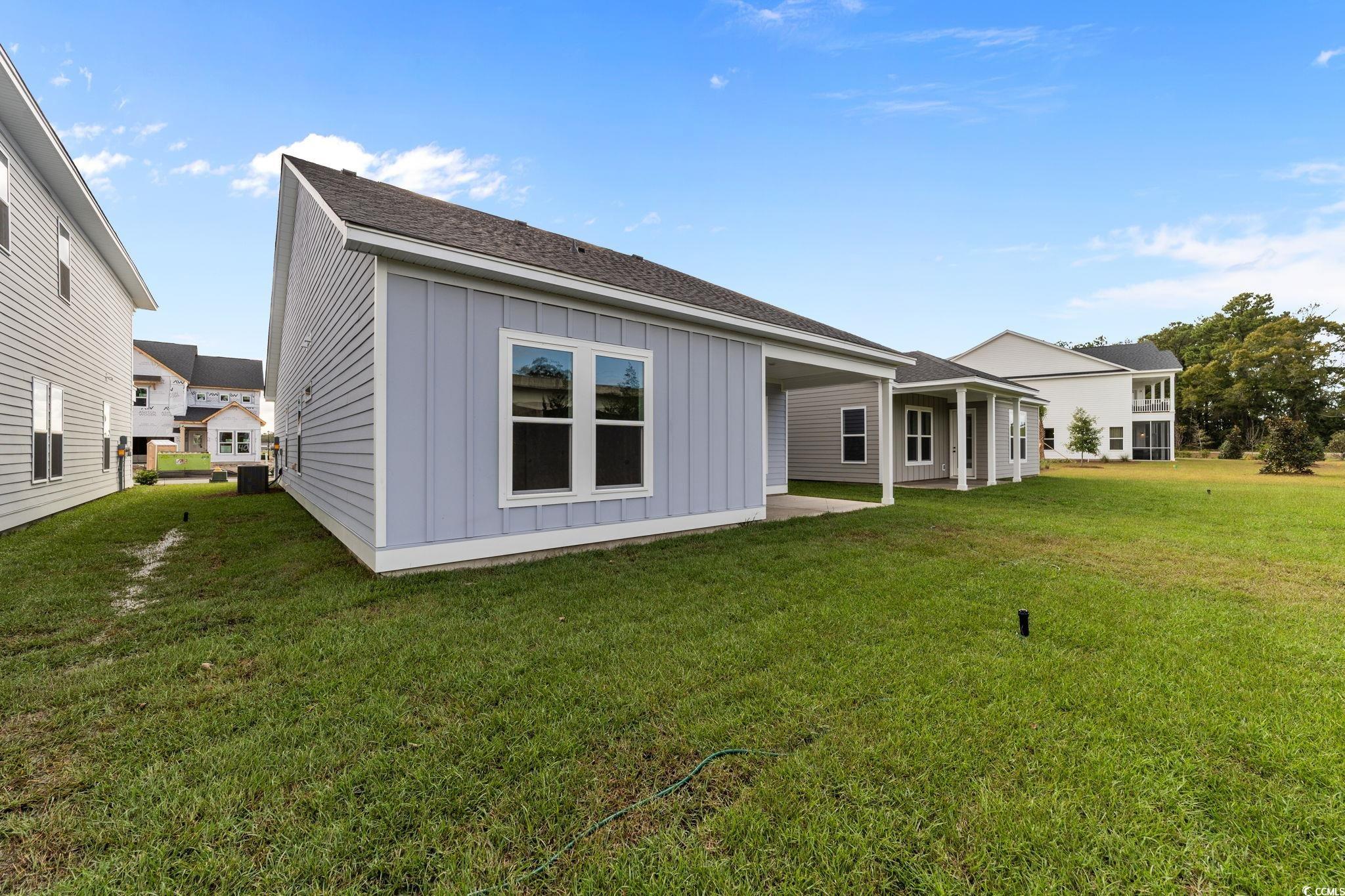 771 Ebb Tide Road Little River, SC 29566 - Photo 5 of 35 Rear view of house featuring board and batten siding, a patio, a lawn, and roof with shingles