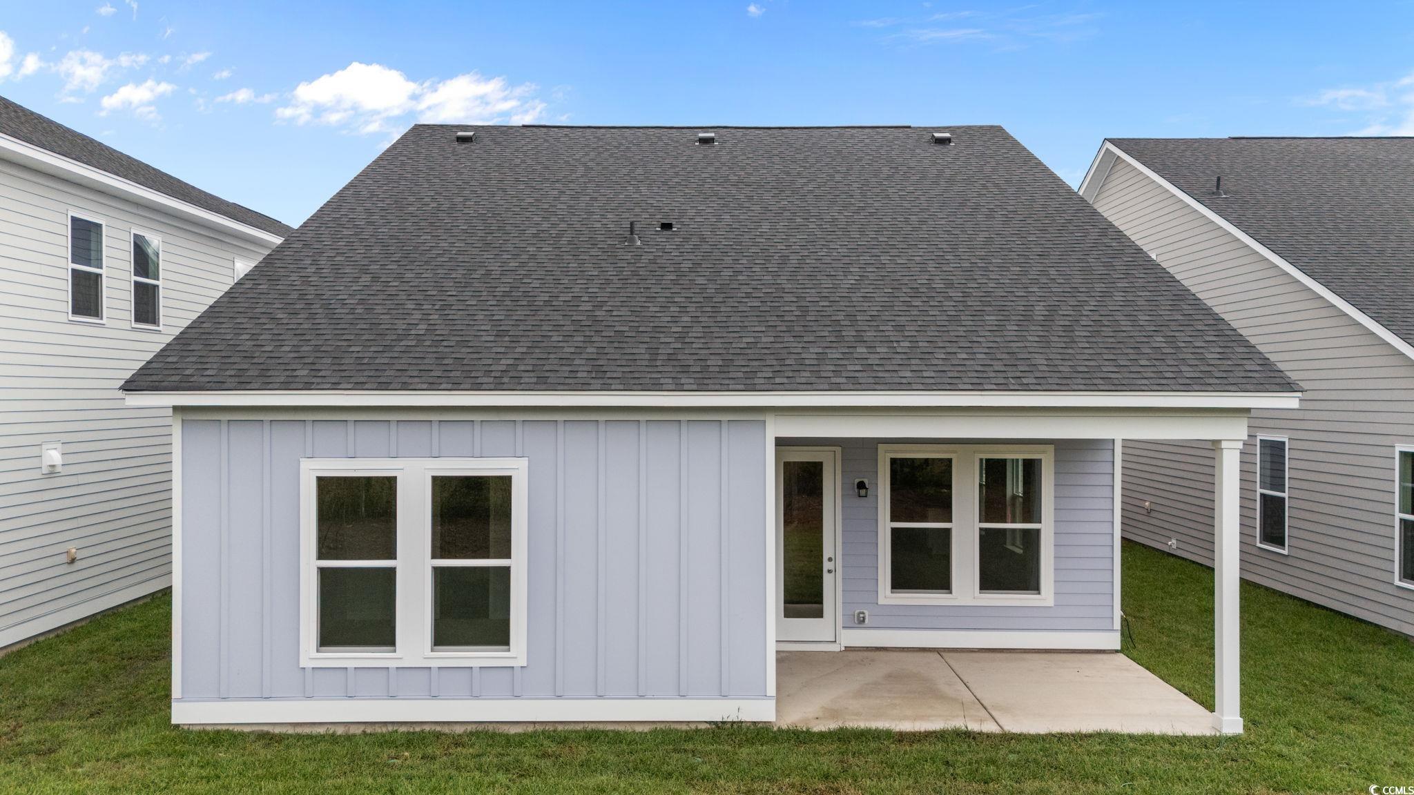 771 Ebb Tide Road Little River, SC 29566 - Photo 7 of 35 Back of property with board and batten siding, a patio, roof with shingles, and a lawn