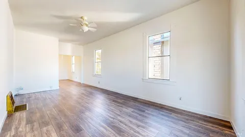 a view of an empty room with wooden floor and a window