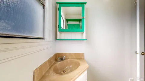 a view of a hallway with wooden floor and a bathroom