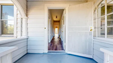 an empty room with wooden floor chandelier fan and windows