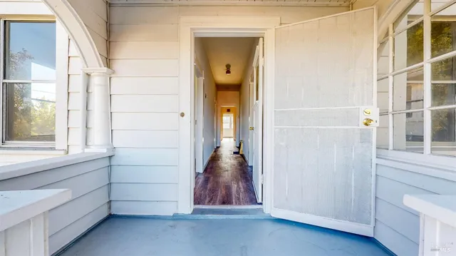 an empty room with wooden floor chandelier fan and windows