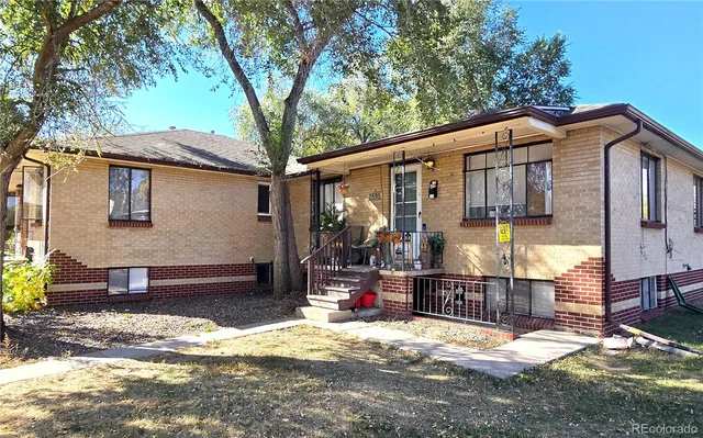 a view of a house with a wooden fence and a tree