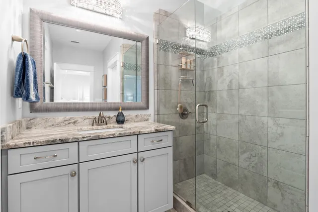 a bathroom with a granite countertop sink a mirror and shower