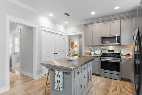 a kitchen with stainless steel appliances granite countertop a stove a sink and a refrigerator with wooden floor