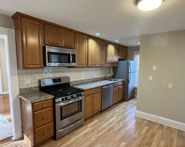 a kitchen with granite countertop stainless steel appliances and wooden cabinets