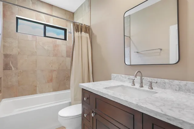 a bathroom with a granite countertop sink a toilet and bathtub