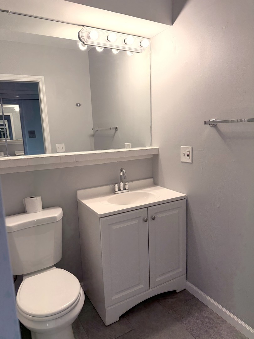 1415 West Pratt Boulevard, Unit 407 Chicago, IL 60626 - Photo 6 of 10 a bathroom with a toilet sink and mirror