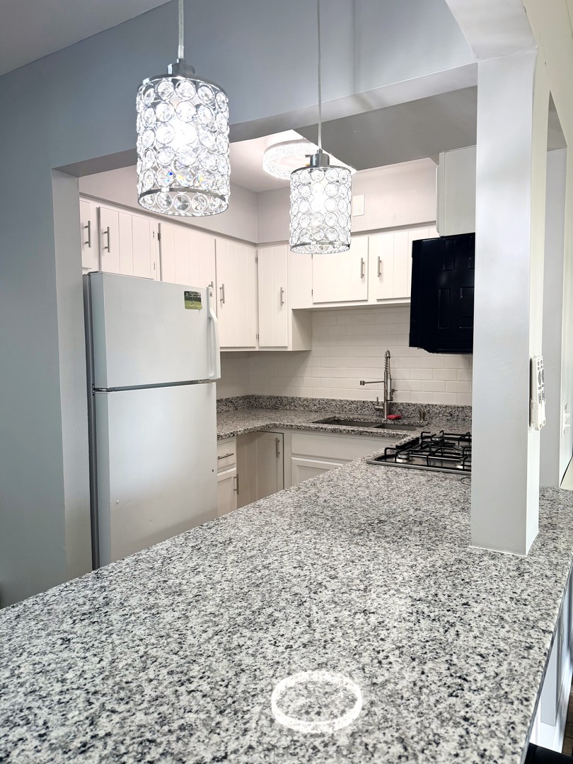 1415 West Pratt Boulevard, Unit 407 Chicago, IL 60626 - Photo 10 of 10 a kitchen with kitchen island granite countertop a refrigerator a stove a microwave and cabinets