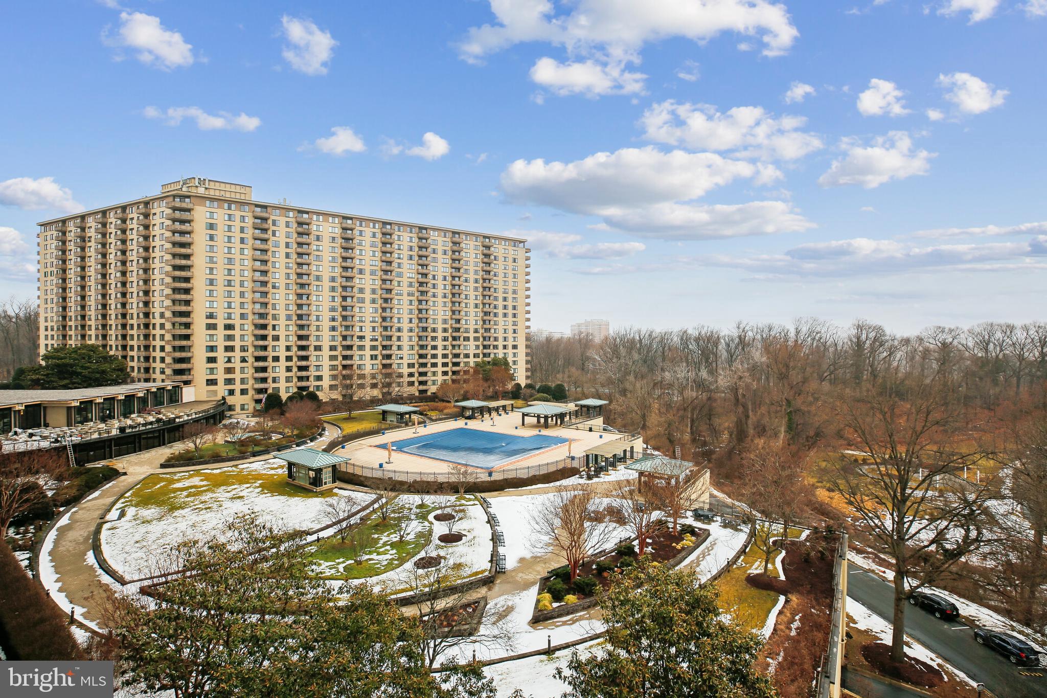 a blue swimming pool with outdoor seating and trees