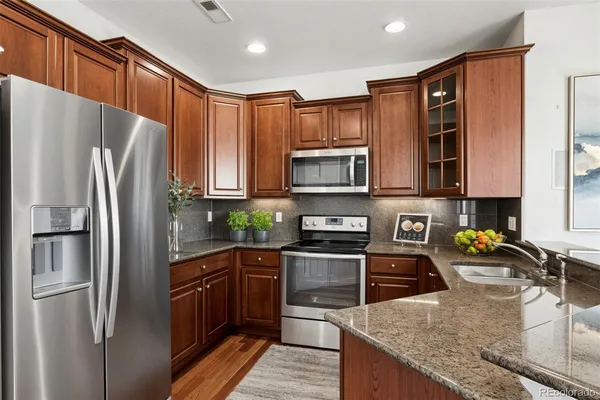 a kitchen with stainless steel appliances granite countertop a refrigerator a stove top oven a sink and dishwasher