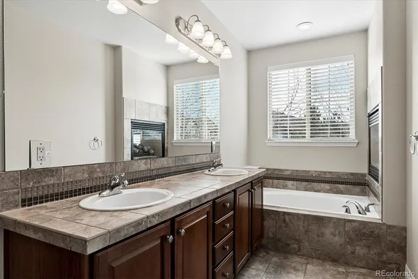 a bathroom with a granite countertop bathtub a sink and a window