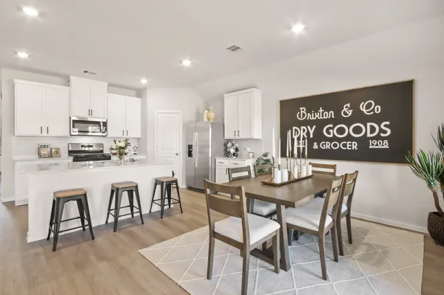 a view of kitchen with stainless steel appliances kitchen island dining table and chairs