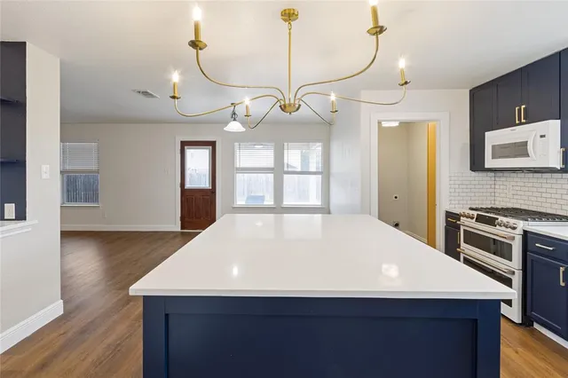 a kitchen with kitchen island a counter space a sink appliances and cabinets