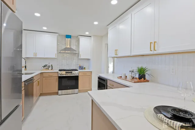 a kitchen with stainless steel appliances white cabinets a sink a stove a refrigerator and a stove