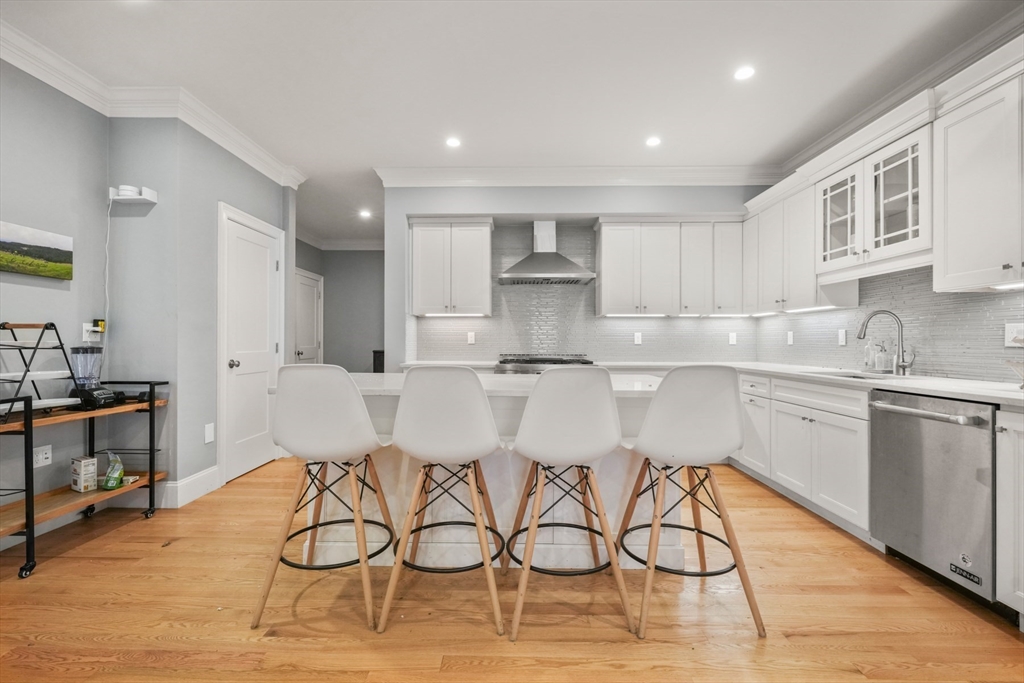 a kitchen with stainless steel appliances kitchen island granite countertop a sink cabinets and wooden floor