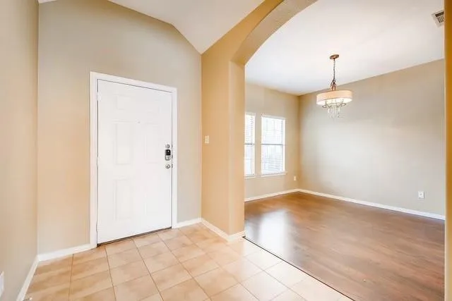 a view of an empty room with window and chandelier fan