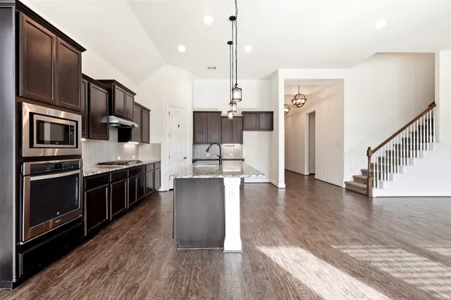 a kitchen with stainless steel appliances kitchen island a stove a refrigerator a sink and a wooden floor