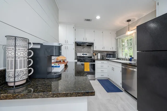 a kitchen with granite countertop stainless steel appliances a stove a refrigerator a sink a counter space and cabinets