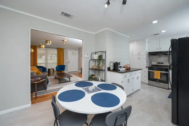 a kitchen with granite countertop kitchen island stainless steel appliances sink dining table and chairs