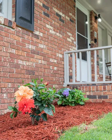a flower is in front of brick house