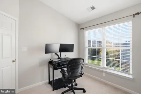 a view of a workspace with furniture and a window